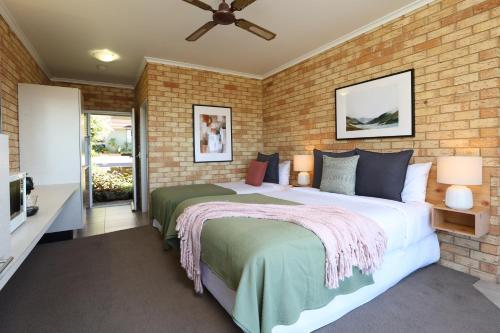 a bedroom with two beds and a brick wall at Maleny Views Motel in Maleny