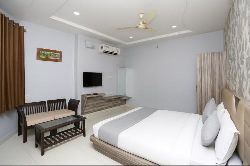 a bedroom with a bed and a chair and a television at Hotel Ramya Village in Gwalior