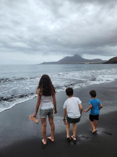 a woman and two children walking on the beach at Casa Fabrice in Ribeira da Prata