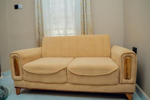 a brown couch sitting in a room with a window at Sweet Homes in Dodoma
