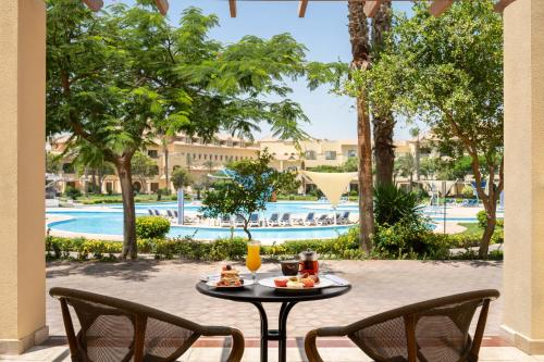 a table with food and drinks on a patio with a pool at Mövenpick Hotel Cairo - Media City in 6th Of October
