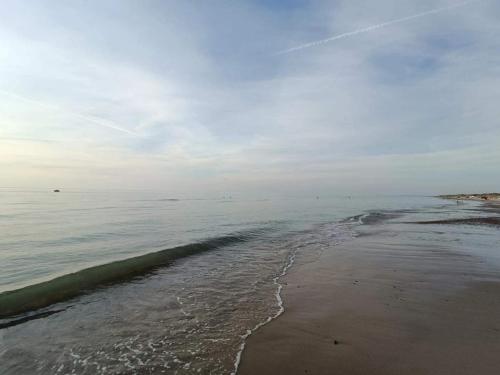 a beach with the ocean on a cloudy day at 6 person holiday home in Brovst in Brovst