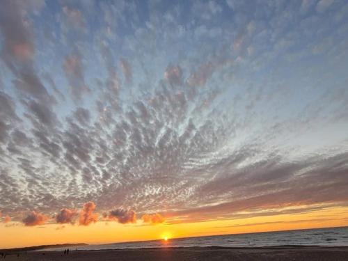 a sunset on the beach with a cloudy sky at 6 person holiday home in Brovst in Brovst