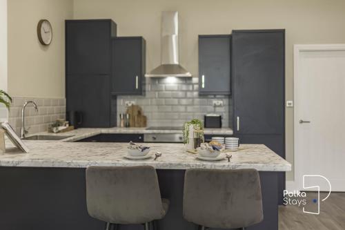 - une cuisine avec des placards noirs et un comptoir en marbre dans l'établissement Luxe Ami Ek South Shore GF Apartment by PolkaStays, à Blackpool