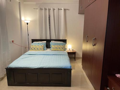 a bedroom with a bed with blue sheets and yellow pillows at Cozy Corner in Bengaluru