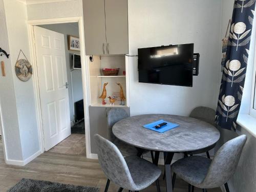 a room with a table and chairs and a tv at Blue Skies in Brading