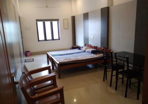 a bedroom with a bed and chairs in a room at Alanchery Residency in Cheruthuruthi