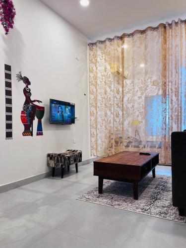 a living room with a table and a tv on a wall at Cozy Studio by HoodSquare- NXone, 15 mins from Central Noida in Jāmb