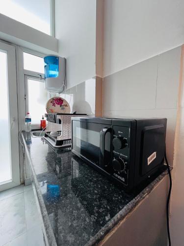 a black microwave on a counter in a kitchen at Cozy Studio by HoodSquare- NXone, 15 mins from Central Noida in Jāmb