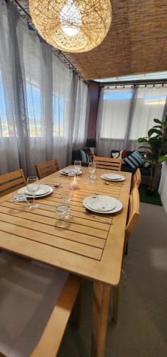 a long wooden table with plates and wine glasses at Nayuha Beach New Penthouse B3 in Flic-en-Flac