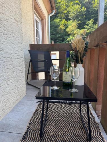 a table with two wine glasses and a bottle at Pfalzliebe Ferienwohnung Emilia in Dahn