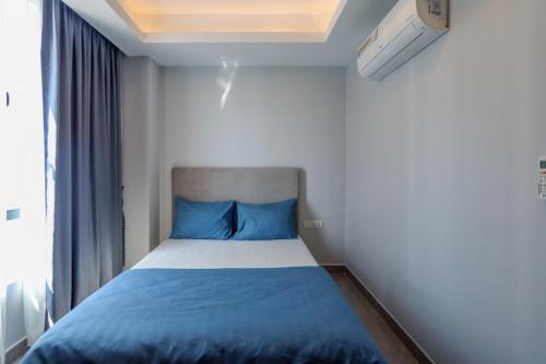 une chambre avec un lit avec des draps bleus et une fenêtre dans l'établissement Modern Apartment with Rooftop Pool & Gym, à Phnom Penh