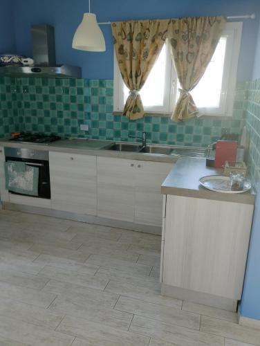 a kitchen with white cabinets and a sink and a window at Imperial casa vacanze in Ladispoli