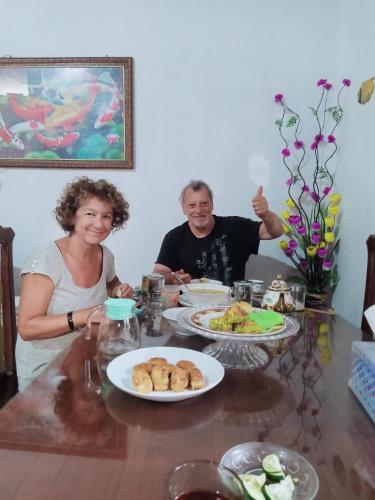 a man and a woman sitting at a table with food at Wambuliga Homestay in Waha