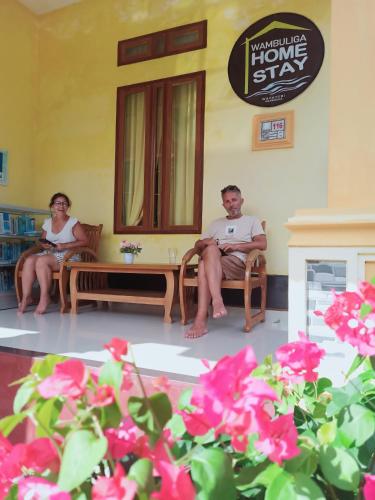 a man and woman sitting in chairs in a room with flowers at Wambuliga Homestay in Waha