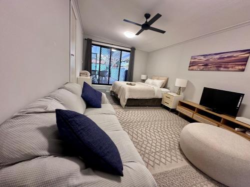 a living room with a couch and a bed at Magnolia Homestead in Coffs Harbour