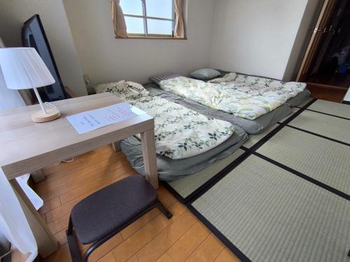 a small room with a bed and a desk with a lamp at 鹿鳴黄金1 in Nagoya
