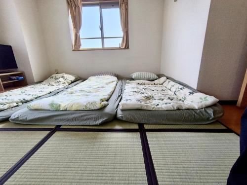 two beds sitting in a room with a window at 鹿鳴黄金1 in Nagoya