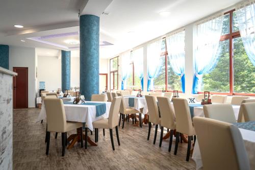 a dining room with tables and chairs and windows at Комплекс Асеневци in Tsareva Livada