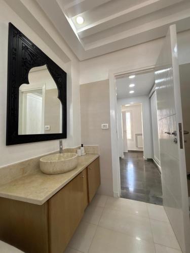 a bathroom with a sink and a mirror on the wall at Villa Le Domaine Djerba Piscine Chauffée sans vis à vis in Mezraya