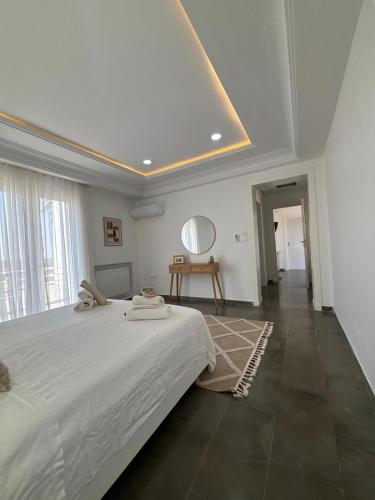 a white bedroom with a large bed and a mirror at Villa Le Domaine Djerba Piscine Chauffée sans vis à vis in Mezraya