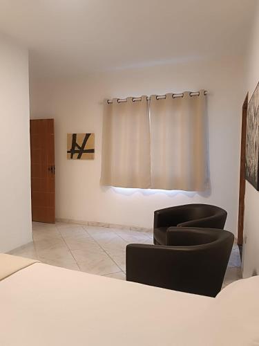 a living room with two chairs and a curtain at UniqueFlats - Casa Mosaico in Nova Iguaçu