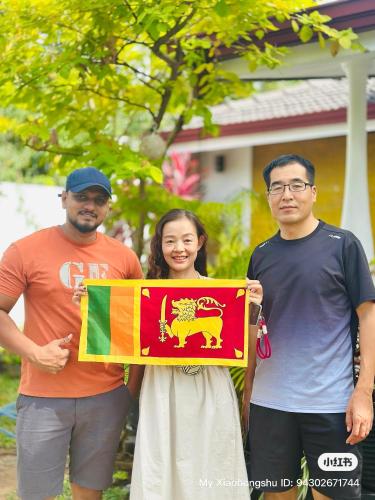two men and a woman holding a flag at White Villa Airport Transit Hotel in Katunayake