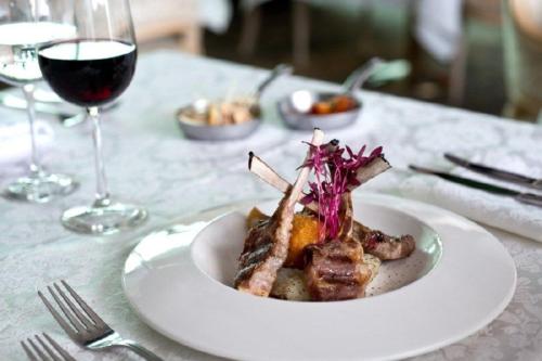 a plate of food on a table with a glass of wine at Herods Palace Hotels & Spa Eilat a Premium collection by Fattal Hotels in Eilat