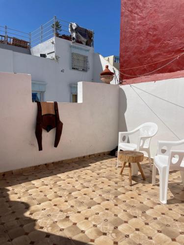a patio with white chairs and a white wall at Zerisurf House in Taghazout