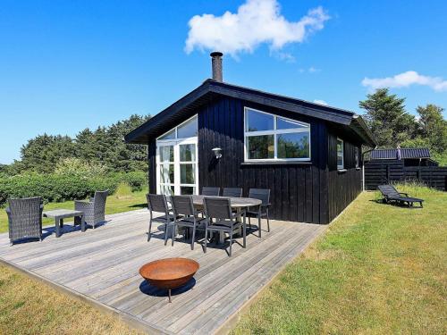 eine schwarze Kabine mit einem Tisch und Stühlen auf einer Terrasse in der Unterkunft 6 person holiday home in Hirtshals-By Traum in Hirtshals
