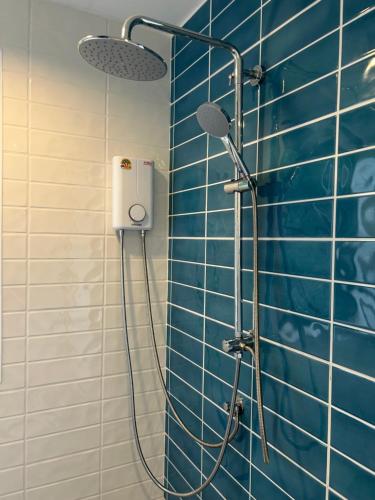 a shower in a bathroom with a blue tiled wall at Little Bird in Prachuap Khiri Khan