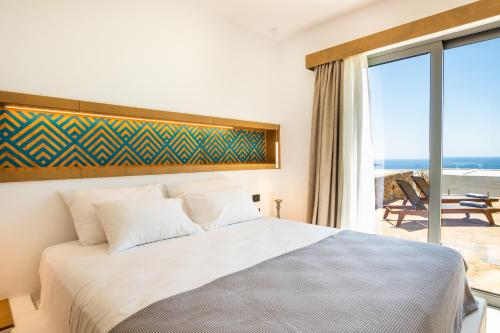 a bedroom with a bed with a view of the ocean at SOPHID Wellness Suites Karpathos in Karpathos Town
