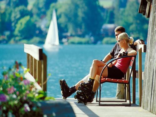 a man and a woman sitting on a dock near the water at Mobile Home in Sachsenburg by River Drau in Sachsenburg