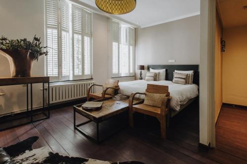 a bedroom with a bed and a table and some windows at Boutique Hotel Stella Maris in Maastricht