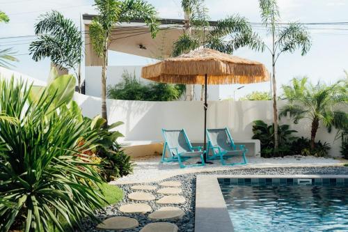 una piscina con 2 sillas azules y una sombrilla en Sunset Serenity Beach House, en Iba