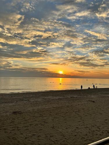 a group of people walking on the beach at sunset at Sunset Serenity Beach House in Iba