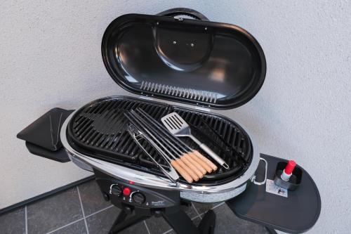 a grill with hot dogs and tongs on it at HK House in Ichinomiya