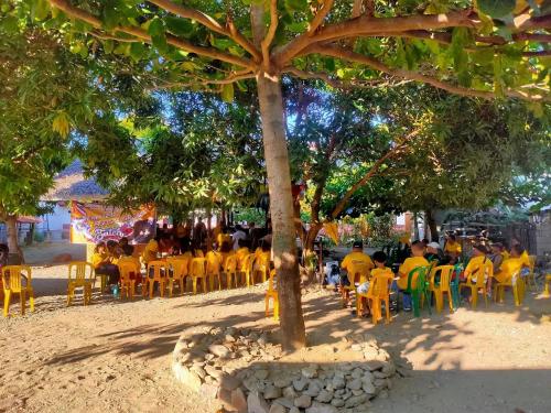 un grupo de personas sentadas en sillas bajo un árbol en Berns Transient Cajidiocan, en Cajidiocan