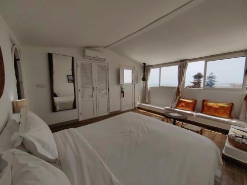 a bedroom with a large white bed and windows at Madada Mogador in Essaouira