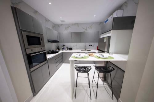 ジッダにあるLuxury two bedroom Apartment As Salamahのキッチン(白いカウンター、スツール2脚付)