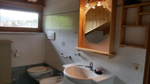 a bathroom with a sink and a toilet and a mirror at Enzian in Sesto