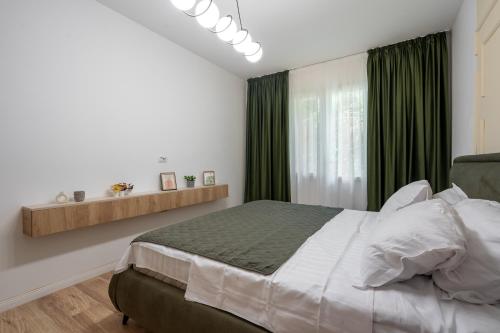 a bedroom with a large bed with green curtains at Rossini King bed i BR Apartment in Bucharest