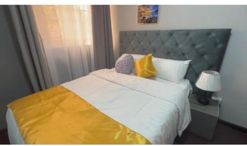 a bedroom with a large bed with yellow and white pillows at Gray House Lodge in Lusaka