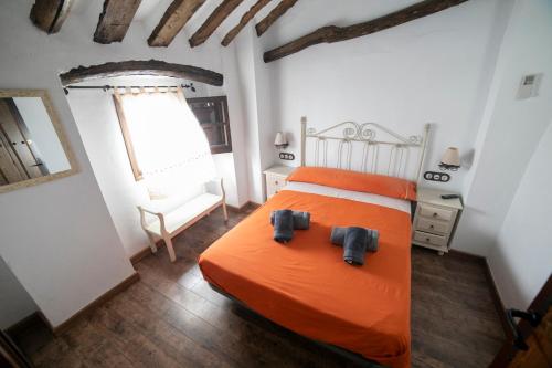 ein Schlafzimmer mit einem orangenen Bett mit zwei Schuhpaaren in der Unterkunft Casa Rural Zambra in Priego de Córdoba