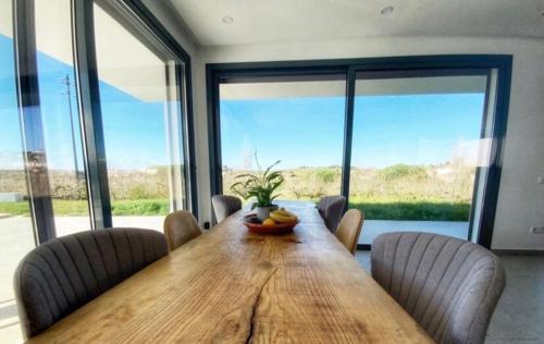 a dining room with a wooden table with chairs and large windows at Bungalow, gated property in amongst Fruit trees, private pool, panoramic views in Bombarral