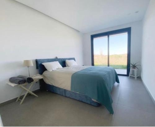 a white bedroom with a bed and a window at Bungalow, gated property in amongst Fruit trees, private pool, panoramic views in Bombarral