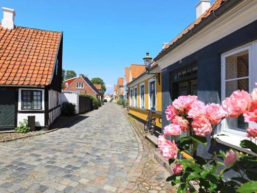 a cobblestone street in a town with pink flowers at 3 person holiday home in Ærøskøbing in Ærøskøbing