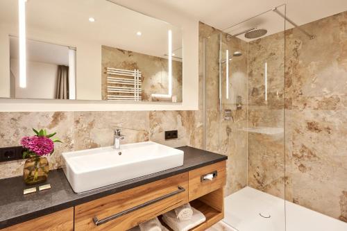 a bathroom with a sink and a shower at Hotel Auf der Gsteig GmbH in Lechbruck