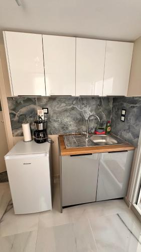 a kitchen with white cabinets and a sink at Steven Eleonas apartments in Eleonas