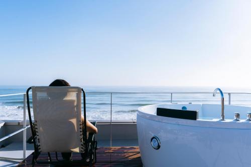 a person sitting in a chair next to a bath tub at COCO VILLA 大洗-Sauna- in Oarai
